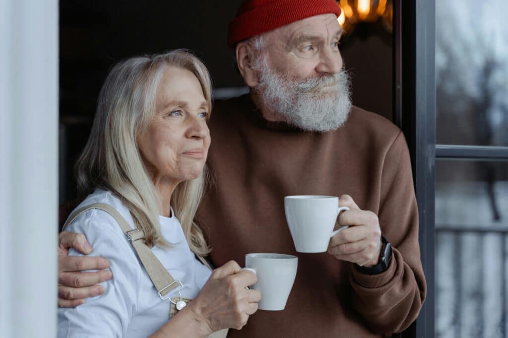 older couple drinking coffee while looking out window